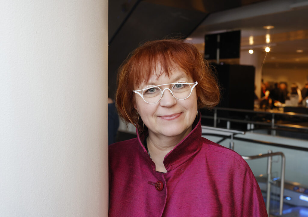 Minnakaisa Kuivalainen hymyilee yllään fuksianpunainen silkkitakki.