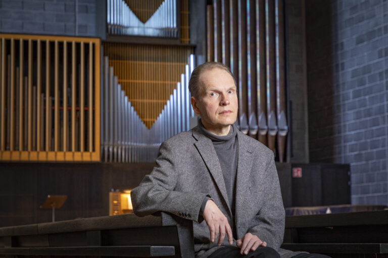 Jyrki Linjama istuu kirkossa urkujen edessä.