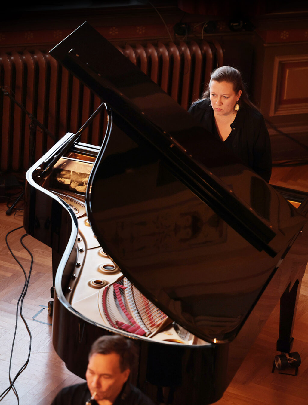 Pianisti soittaa flyygeliä, jonka kansi on auki ja kielistö näkyvissä.